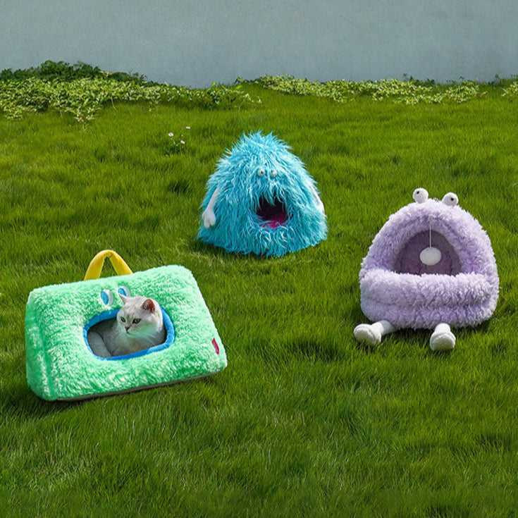 Monster Series Cat Bed in green, blue, and purple monster designs placed on grass, ideal for playful and cozy cat lounging.