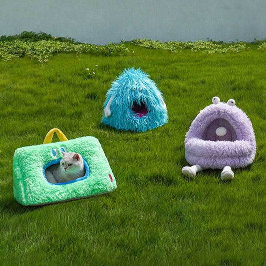 Monster Series Cat Bed in green, blue, and purple monster designs placed on grass, ideal for playful and cozy cat lounging.
