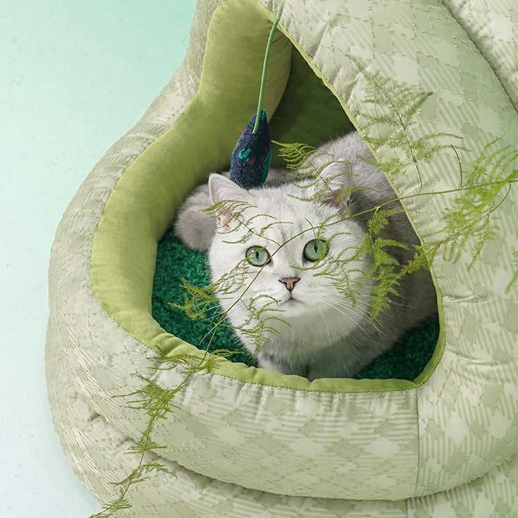 Cat inside Green Pine Cave Cat Bed - Japanese Design, showcasing the cozy interior and playful hanging toy for feline comfort.