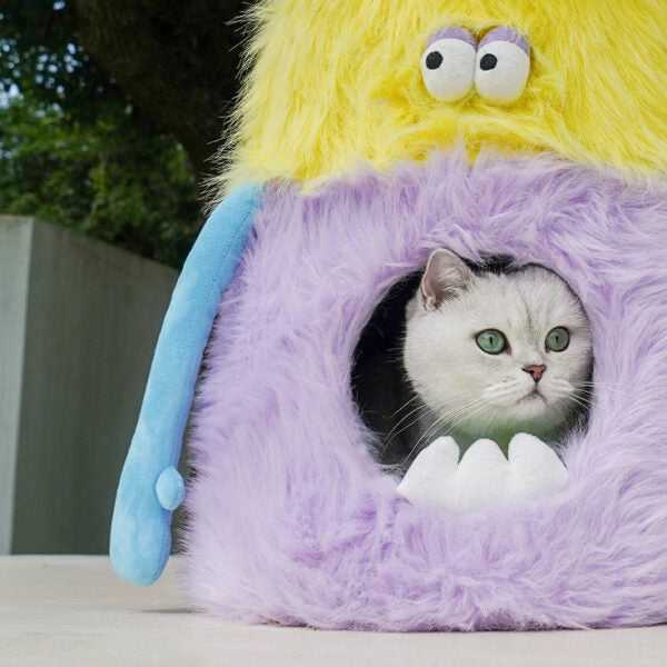 Close-up of a cat inside the Little Monster Stool Cat Bed with visible plush monster teeth and soft furry texture.