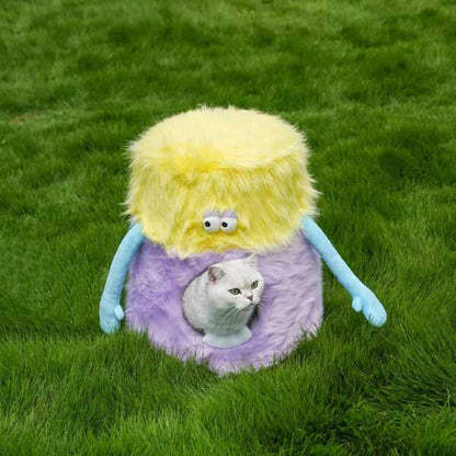 Little Monster Stool Cat Bed on green grass with a cat peeking out. Plush and playful cat furniture for indoor or outdoor use.
