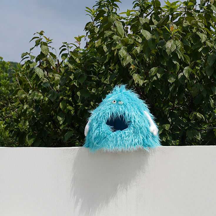 Blue Monster Series Cat Bed with fluffy monster design placed on a white wall, emphasizing its whimsical and eye-catching style.