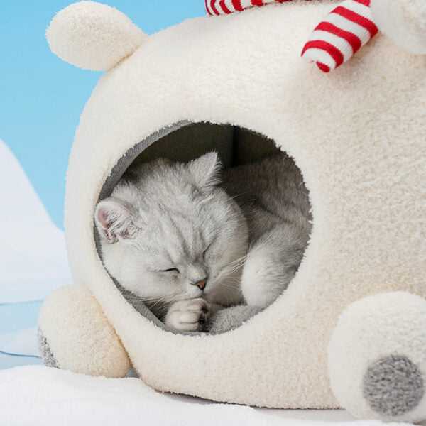 Sleeping cat nestled in Polar Bear Cat Bed - Cozy Winter Retreat, made of soft velvet and foam for heat retention during cold seasons.