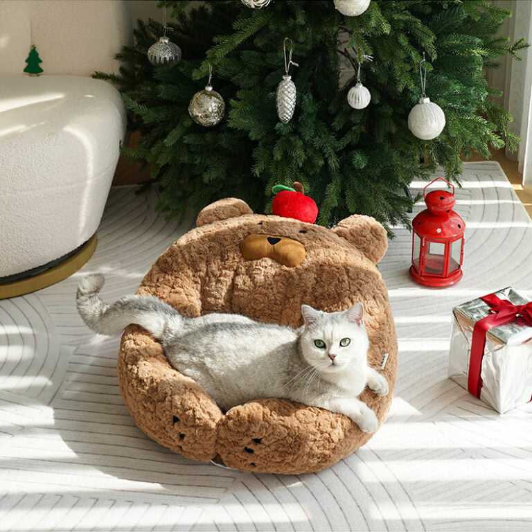 Cat lounging in Apple Bear Hug Cat Bed under Christmas tree, highlighting cozy and festive pet furniture.