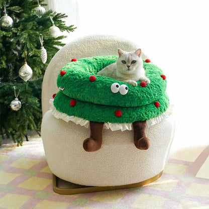 Cat sitting atop Christmas Wreath Shaped Cat Bed placed on a chair, blending pet comfort with festive home decor.