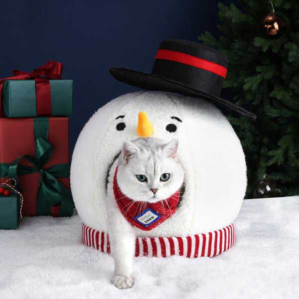 White cat stepping out of Snowman Cat Covered Bed, wearing red plaid harness, showcasing cozy pet bed design.
