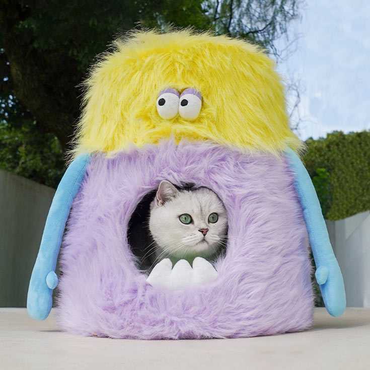 Little Monster Stool Cat Bed with a cat inside, placed outdoors. Features soft fur and monster eyes for playful cat lounging.