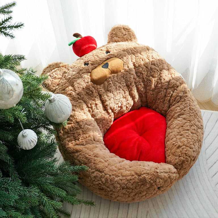 Top view of Apple Bear Hug Cat Bed near Christmas tree, showing plush bear design and vibrant red cushion.