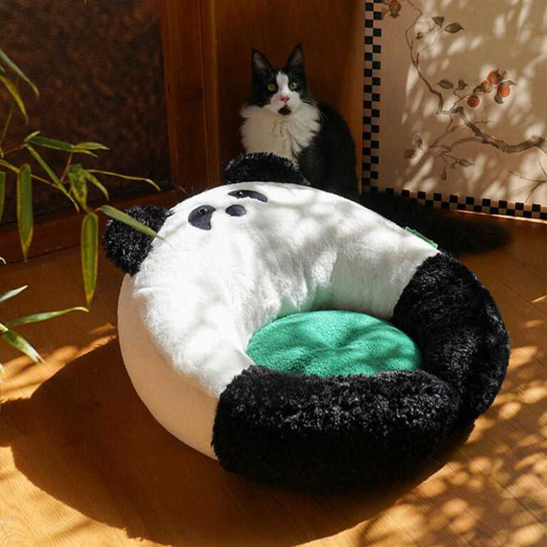 Panda Hug Cat Bed in sunlight with a black and white cat nearby, highlighting its soft panda design and inviting green cushion.