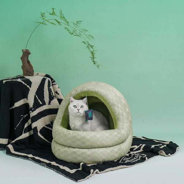 Cat peeking from Green Pine Cave Cat Bed - Japanese Design, placed on black patterned blanket for cozy and stylish pet space.