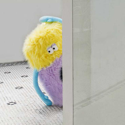 Little Monster Stool Cat Bed peeking from behind a wall, showcasing its quirky monster design with plush texture and blue arms.