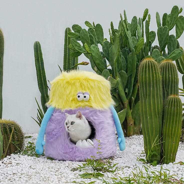 Little Monster Stool Cat Bed with a cat inside, placed among cacti. Unique cat furniture combining comfort and whimsical design.