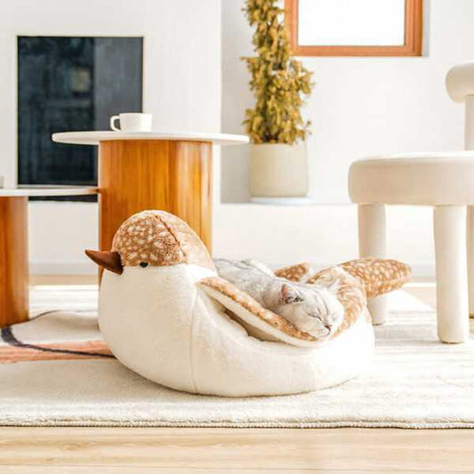 Sparrow Cat Bed in bird shape with a sleeping cat inside, placed in a modern living room. Cozy and stylish cat furniture for pet comfort.