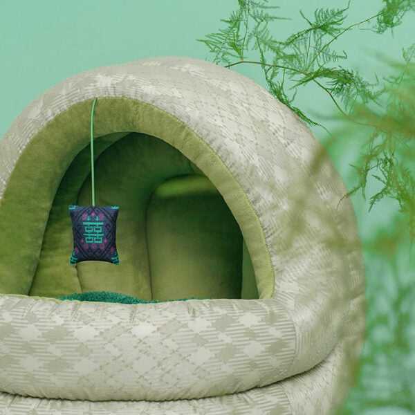 Side view of Green Pine Cave Cat Bed - Japanese Design with hanging toy, emphasizing soft texture and modern pet furniture.