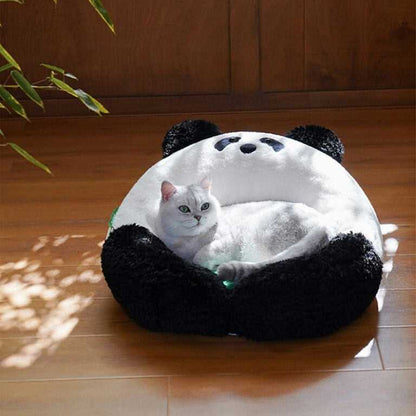 White cat resting in the Panda Hug Cat Bed on a wooden floor, highlighting the cozy panda design and soft green cushion.